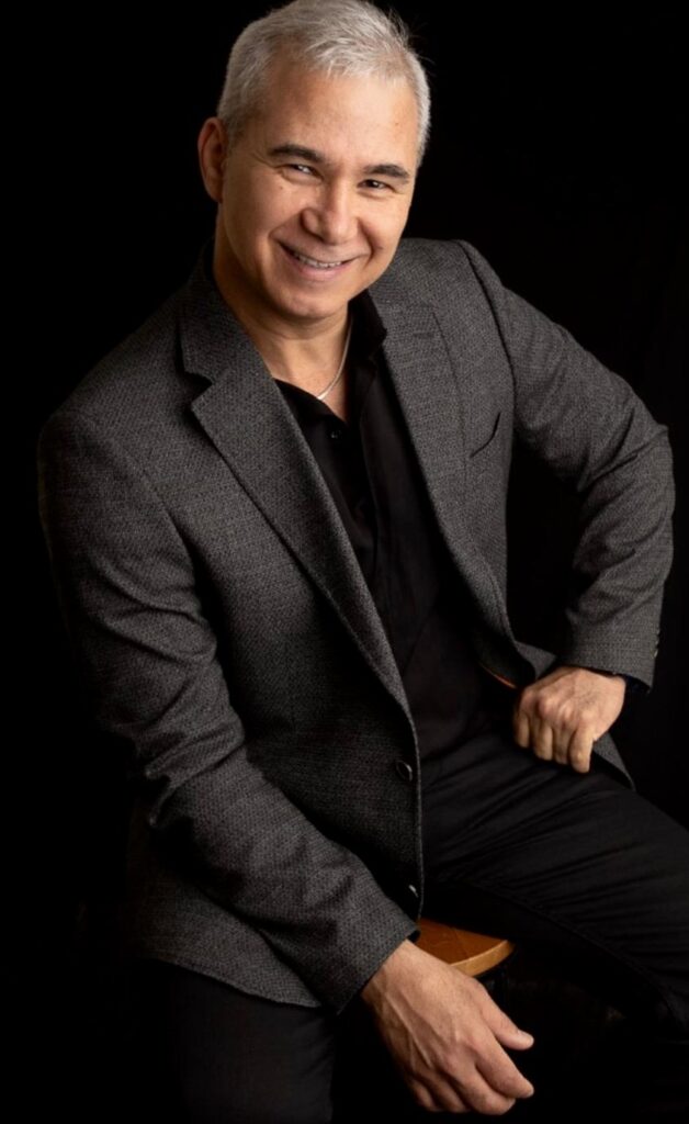 Joel F. Jr., Owner and Client Manager of Shiny Cleaning Crew, smiling in a professional portrait wearing a gray blazer and black shirt